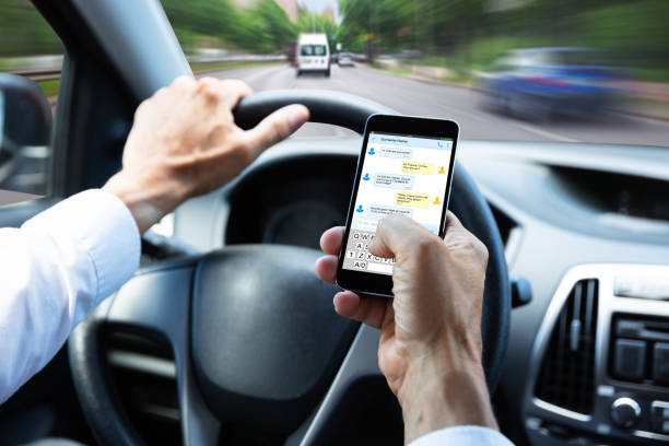 Close Up Of A Man's Hand Typing Text Message On Mobile Phone While Driving Car
